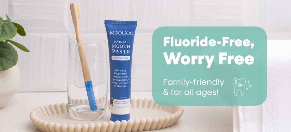 An image of MooGoo's Flouride-Free Moothpaste sitting beside a glass and tooth brush on a bathroom vanity