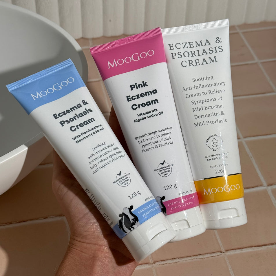 MooGoo Eczema and Psoriasis Cream Marshmallow Elderberry, Eczema and Psoriasis Cream Gotu Kola Chamomile, and Pink Eczema Cream Vitamin B12 held in one hand, soothing cream for sensitive eczema and psoriasis prone skin.