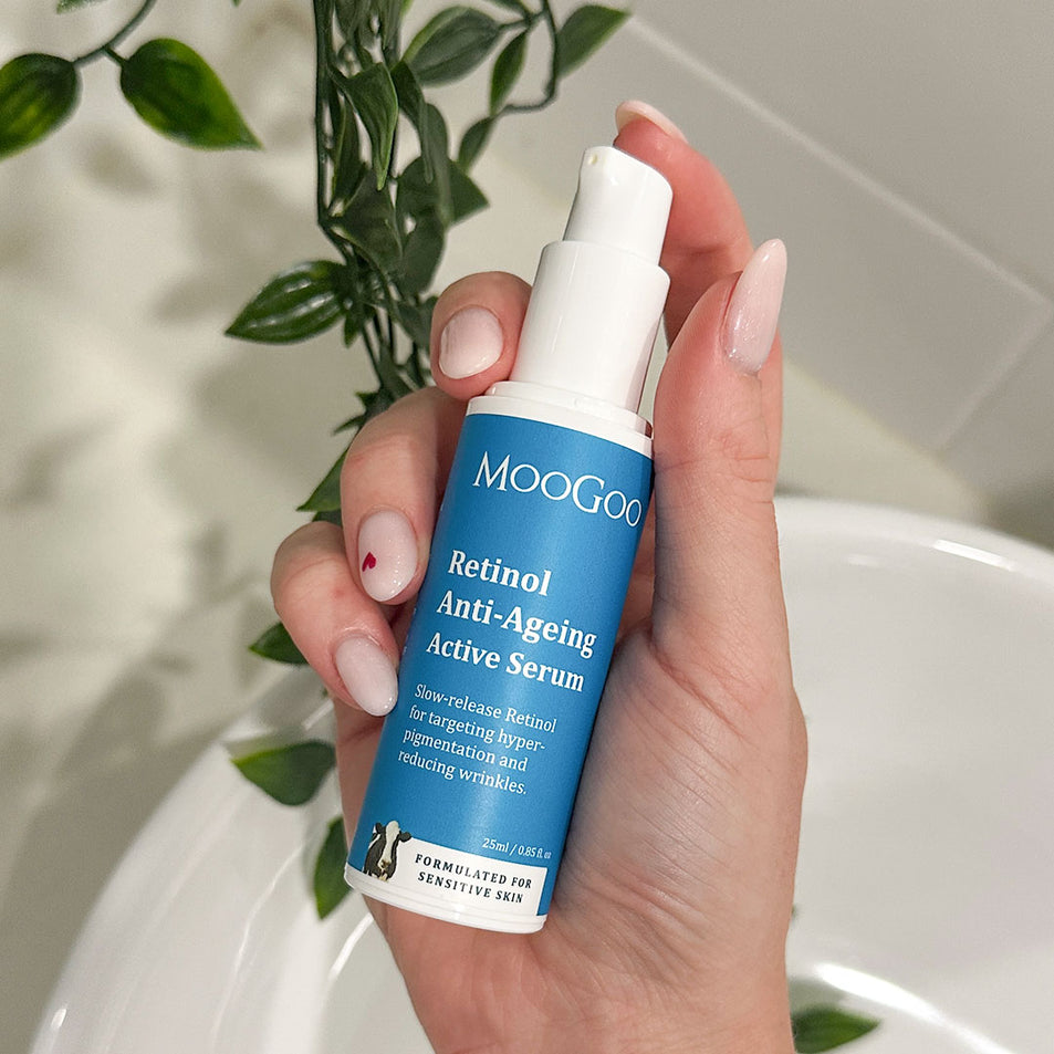 Hand holding a Moogoo Retinol Anti-Ageing Active Serum bottle with a plant in the background