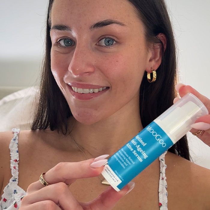 Woman holding a Moogoo skincare product with a plain background