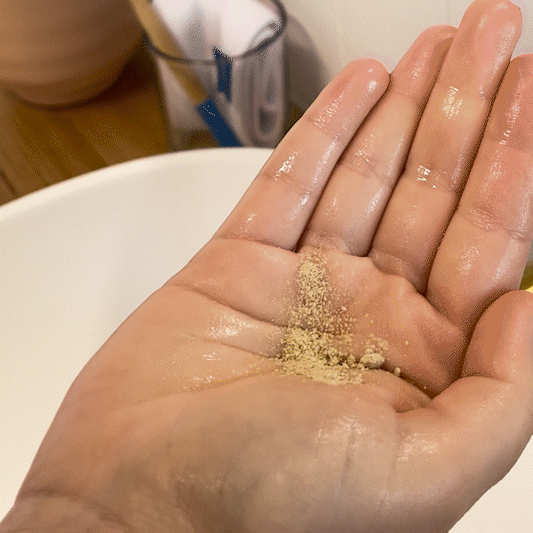 Woman applying MooGoo Gentle Exfoliating Micro Powder to face, salicylic acid facial exfoliant with rice bran powder, gently exfoliates and smoothens skin.