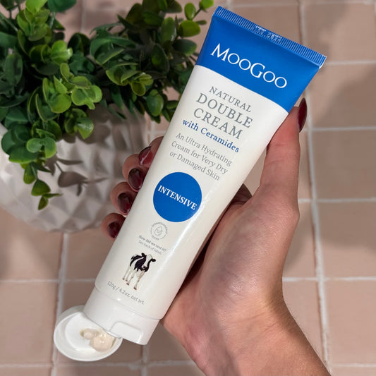 MooGoo Natural Double Cream with Ceramides held above tiled floor, intensive cream for dry flaky or damaged skin repair and barrier support with natural hydration.