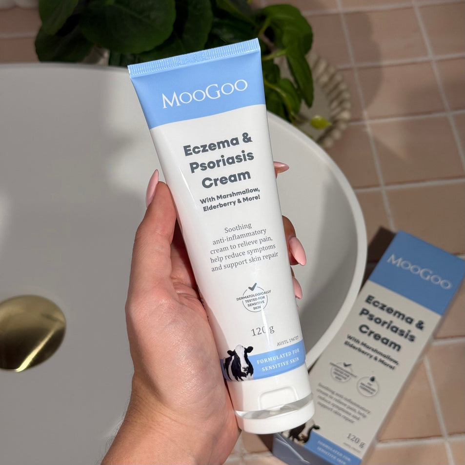 MooGoo Eczema & Psoriasis Cream held above tiled floor, soothing natural anti inflammatory cream with marshmallow and elderberry for sensitive skin