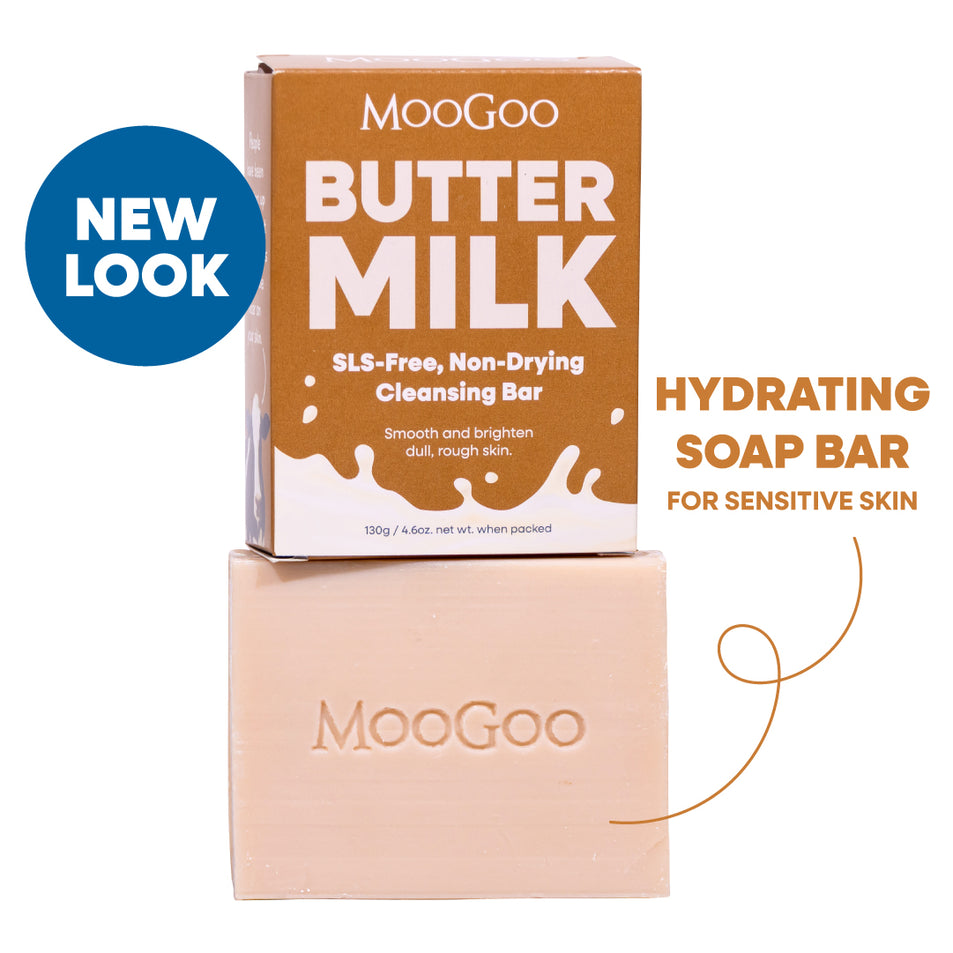 MooGoo Butter Milk SLS-Free Non-Drying Cleansing Bar shown with its brown cardboard box and the pale peach soap bar stacked below. A blue circular 'NEW LOOK' badge appears on the left, and text on the right reads 'HYDRATING SOAP BAR FOR SENSITIVE SKIN'. MooGoo Buttermilk Soap alternative, hydrating cleansing bar for dry skin, natural oils, SLS free and gentle on sensitive ski