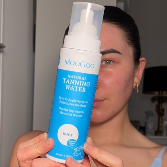 MooGoo Tanning Water Body shown in hand, natural spray tan solution for healthy looking skin, fast absorbing and non-irritating.