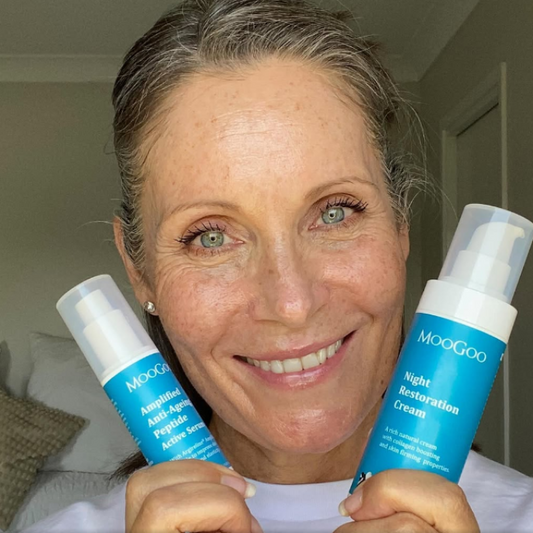 happy woman holding MooGoo Amplified Anti-Ageing Peptide Active Serum 25ml and Night Restoration Cream 75g, her expression lines are diminished and reduced.